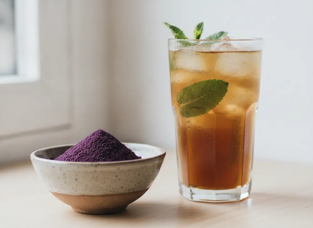 A glass of iced yerba mate with mint next to a bowl of acai powder