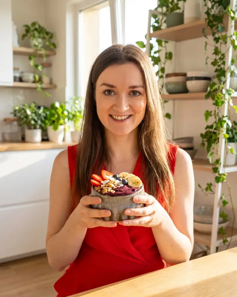 Woman in a red dress holding an açaí bowl with fruit