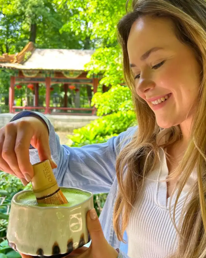 Woman whisking matcha with a chasen in a sunny garden