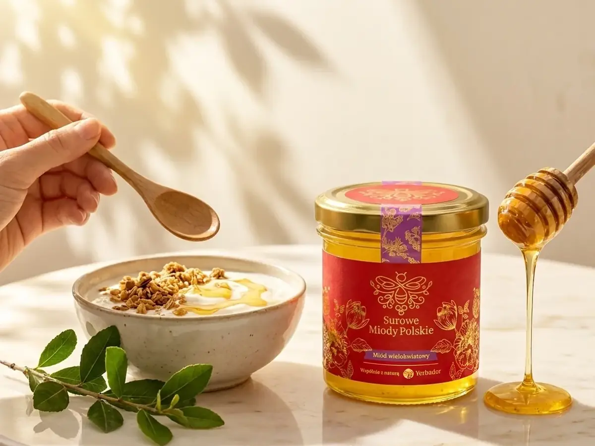 Honey dripping from a spoon next to a Yerbador jar and a bowl of yogurt with granola
