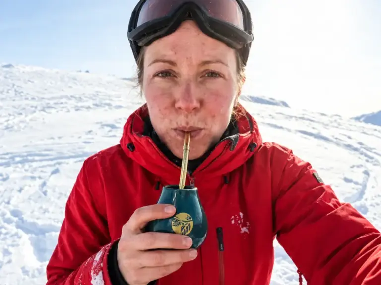 Female skier drinking yerba mate from a matero on a snowy slope
